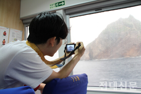 학생이 울릉도로 돌아가는 배 안에서 독도 사진을 찍는 모습. 