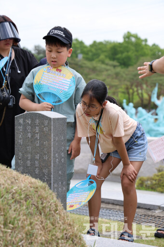 지난 4일 국립5·18민주묘지 신묘역에서 '광주 동구의 오월 기억 여행'에 참가한 학생들이 해설을 들으며 묘비에 새겨진 내용을 읽고 있다.