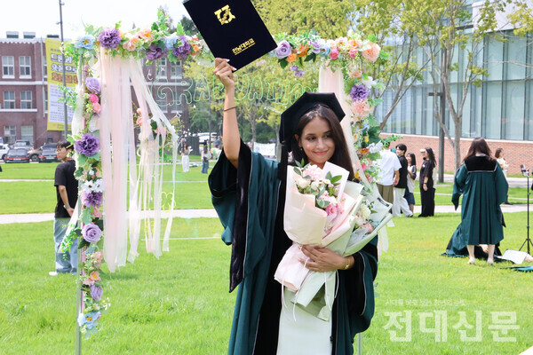 26일 후기 학위수여식에 참여한 졸업생이 5·18광장(봉지)에서 학위복을 입고 포즈를 취하고 있다.