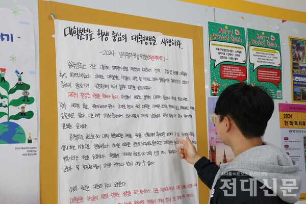 우리 대학 제1학생마루에 걸린 학점비율조정 규탄 대자보를 읽고 있는 김우진씨의 모습.