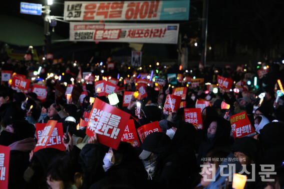 지난 7일 서울 여의도 국회 앞에 앉아 대형스크린을 통해 윤석열 대통령 탄핵안 표결을 기다리는 시민의 모습이다.