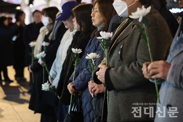 시민들이 분향소 앞에서 국화 한 송이씩을 들고 있다. 