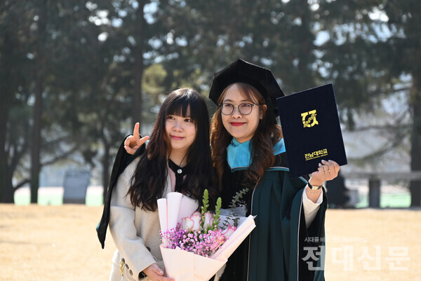 민주마루 앞에서 졸업생이 포즈를 취하고 있다.