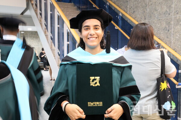 지난 26일 후기 학위수여식에 참여한 졸업생이 민주마루 내부에서 학위복을 입고 졸업장을 들고 있다.