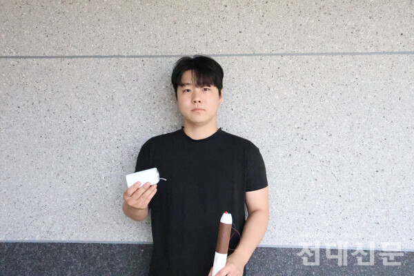 이창민씨가 직접 개발한 점자 인쇄기와 스마트 점자 지팡이를 들고 있는 모습.