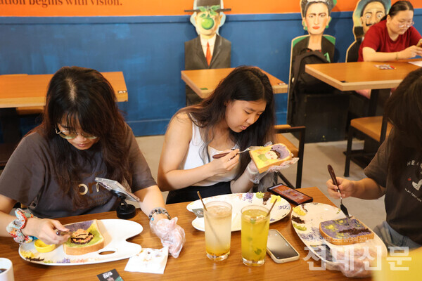 부부카페에서 방문자들이 식빵에 그림을 그리고 있다.