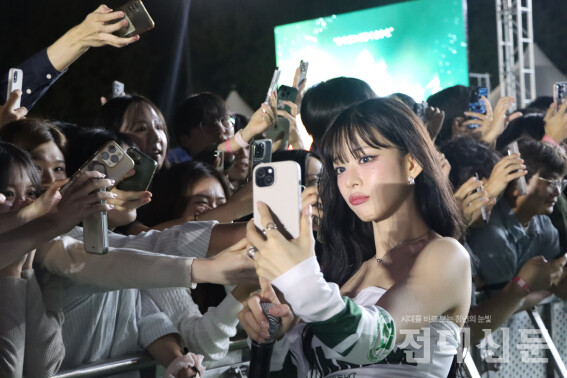 프로미스나인 이채영씨가 학생들의 핸드폰으로 사진을 찍고 있다.