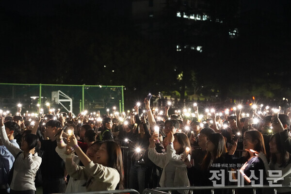 학생들이 휴대폰 후레쉬를 켜고 무대를 향해 흔들고 있다.